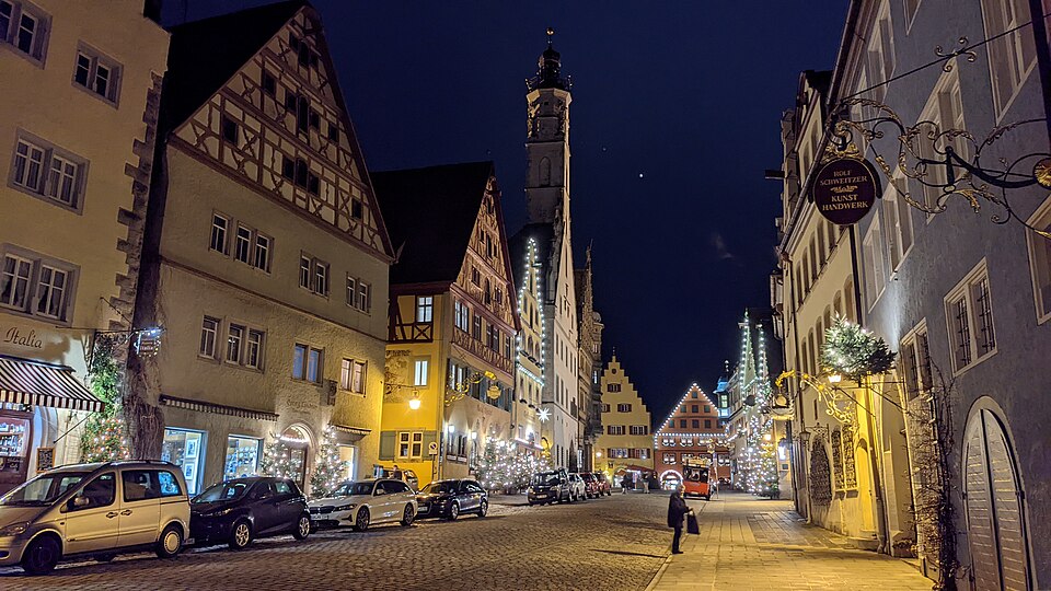 The wide Herrngasse of Rothenburg illuminated at night during the Christmas season.